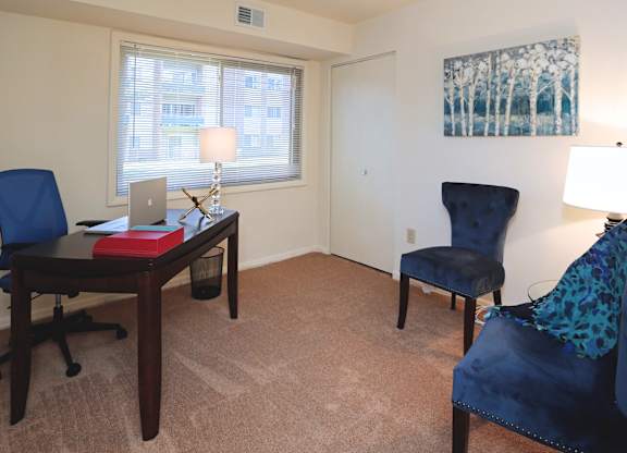 Room with a desk, chair, and painting on the wall.