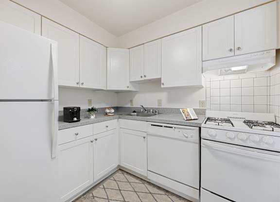 A white kitchen with a refrigerator, stove, and cabinets.