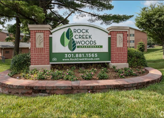 A sign for Rock Creek Woods Apartments is shown in front of a building.
