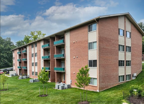 A red brick apartment building with a green lawn in front.