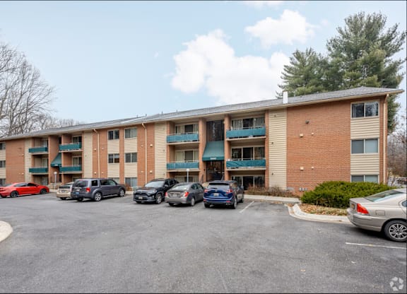 A parking lot in front of a multi-story apartment building.
