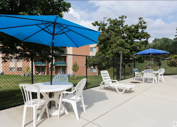 A blue umbrella is over a white table and chairs.