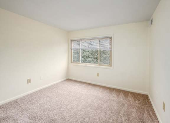 A room with a window and carpeted floor.