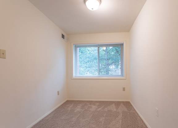 A room with a window and carpeted floor.