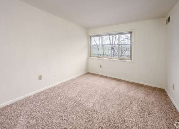 A room with a carpeted floor and a window.