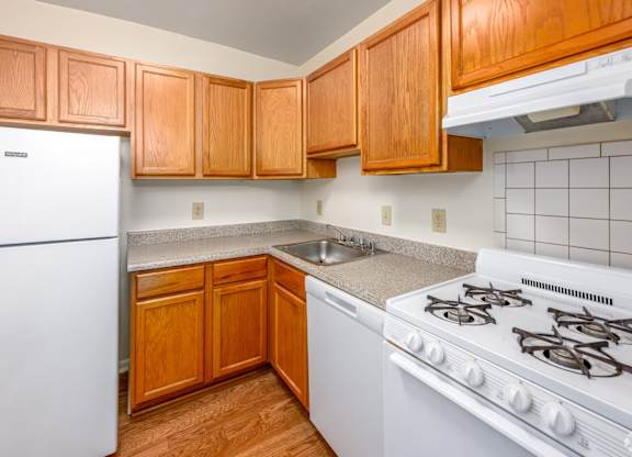 A kitchen with wooden cabinets and a white stove.