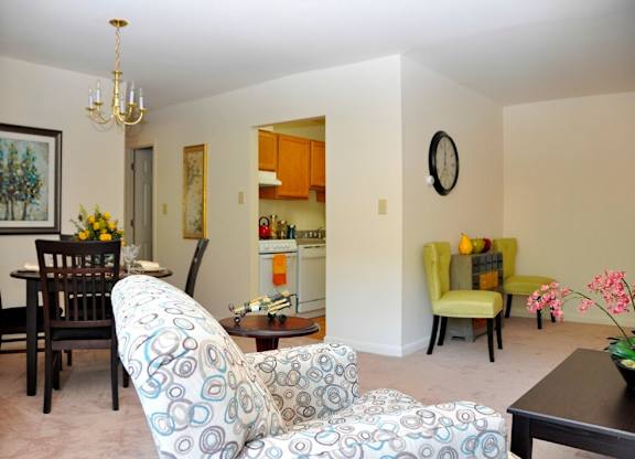 A living room with a sofa, chairs, and a painting on the wall.