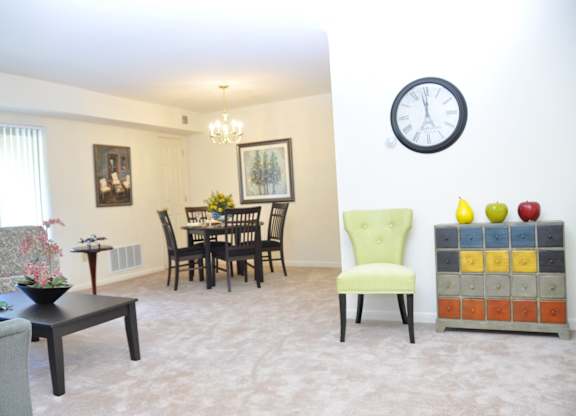 A dining room with a green chair and a chandelier.