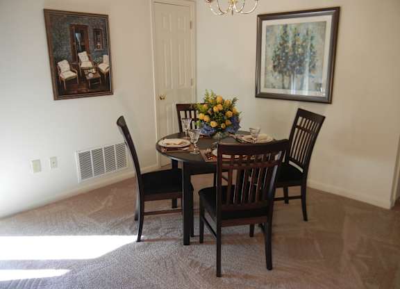 A dining room with a table set for four.