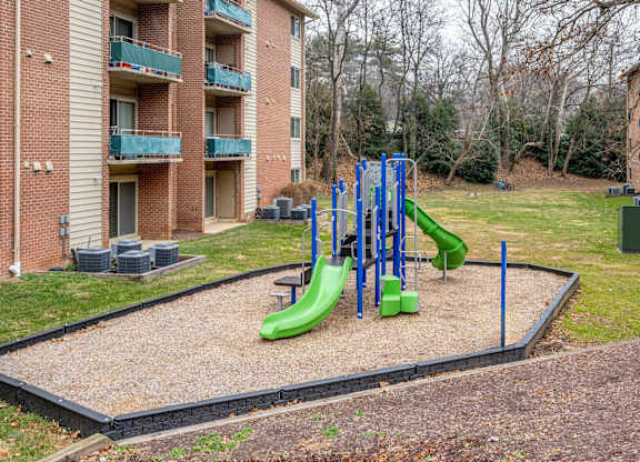 A playground with a green slide and blue poles.