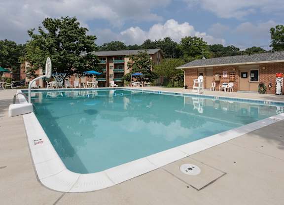 A large outdoor swimming pool with a white fence and a building in the background.