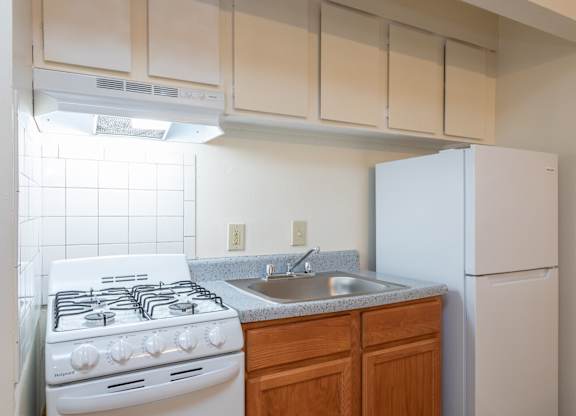 A white gas stove with a white refrigerator in a kitchen.