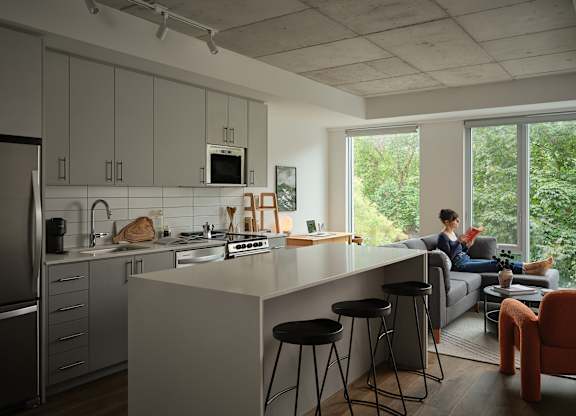 a kitchen and living room with a person sitting on a couch