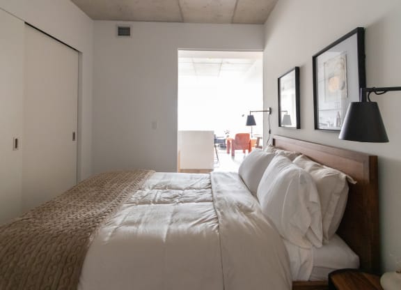 a bedroom with a bed and a door to a living room