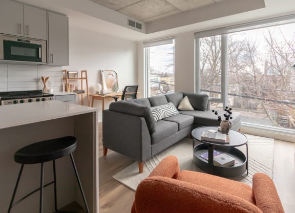a living room with a couch and a kitchen with a large window