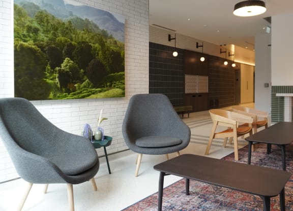 a living room with chairs and tables and a painting on the wall