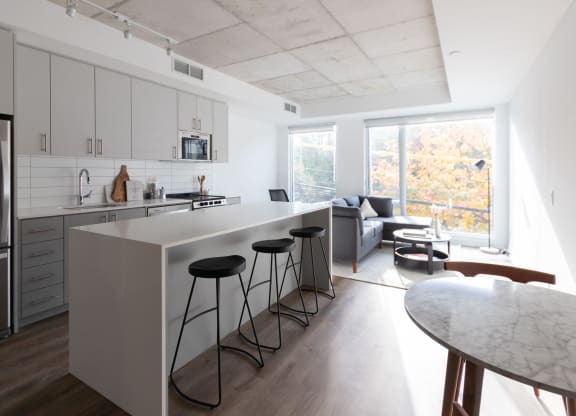 a kitchen with a long island and three stools in front of a white counter