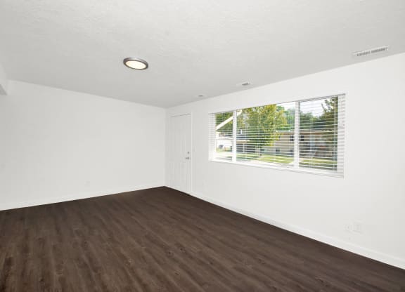 an empty living room with wood floors and a window