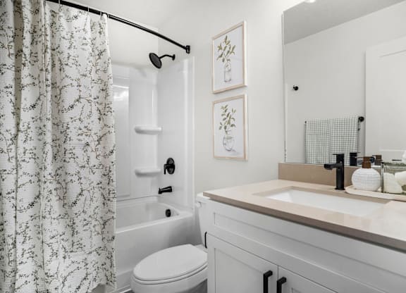 A white bathroom with a toilet, sink, and shower.