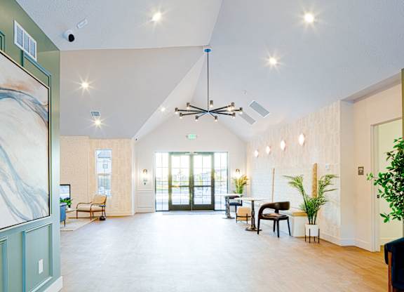 A spacious room with a high ceiling and a large painting on the left side.