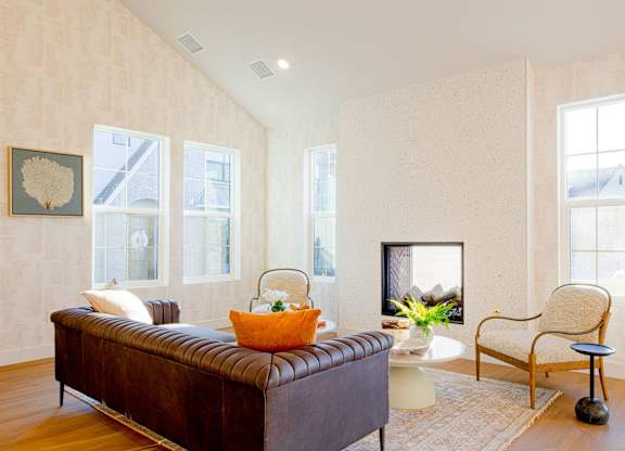 A living room with a brown leather couch, a white side table, and a chair.