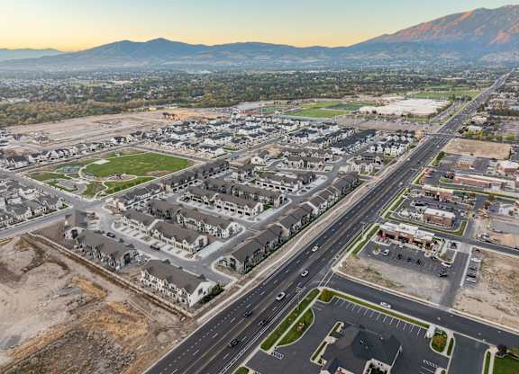 A large, modern housing development is under construction in a valley with mountains in the background.