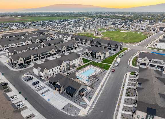 A sunset view of a residential area with houses and a pool.