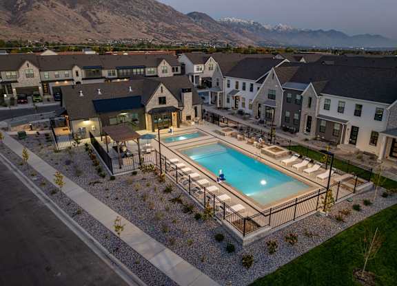 A swimming pool surrounded by a fence and a few chairs.
