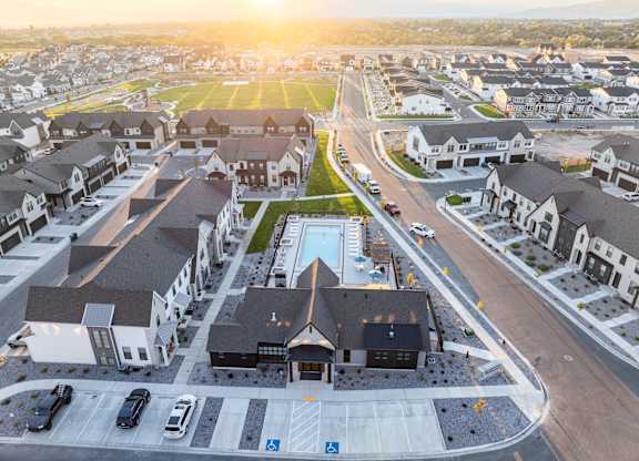 A sunset view of a residential area with houses and a swimming pool.