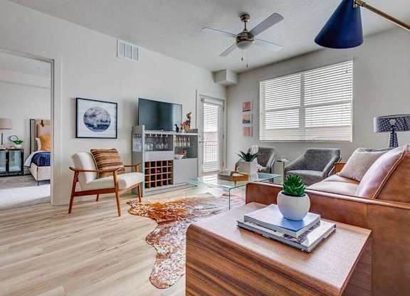 A living room with a brown couch, a wooden coffee table, and a ceiling fan.