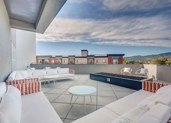 A white couch is on a patio with a table and chairs.