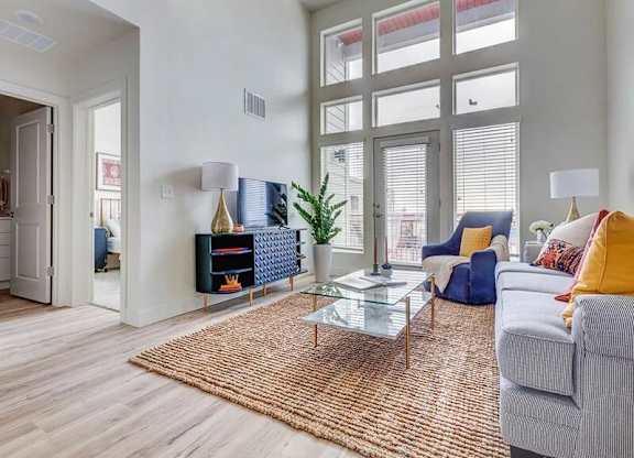 A living room with a grey couch, a blue chair, a glass coffee table, and a rug.