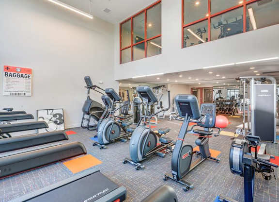 A gym with a variety of exercise equipment including treadmills, stationary bikes, and weight machines.
