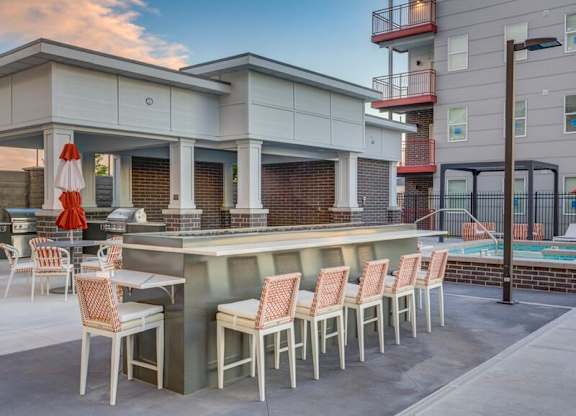 A patio with a bar and chairs is set up outside a building.
