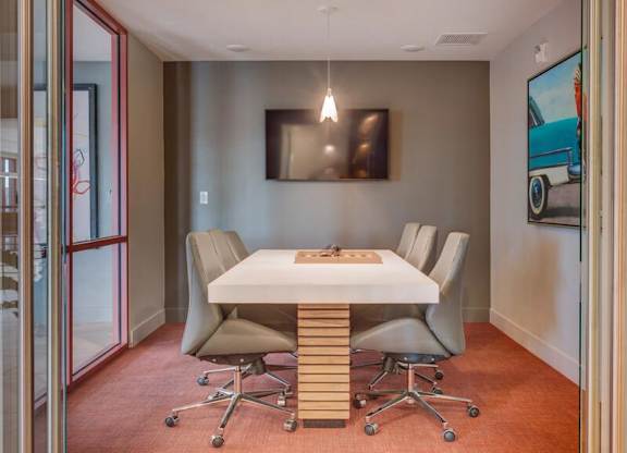 A conference room with a white table and grey chairs.