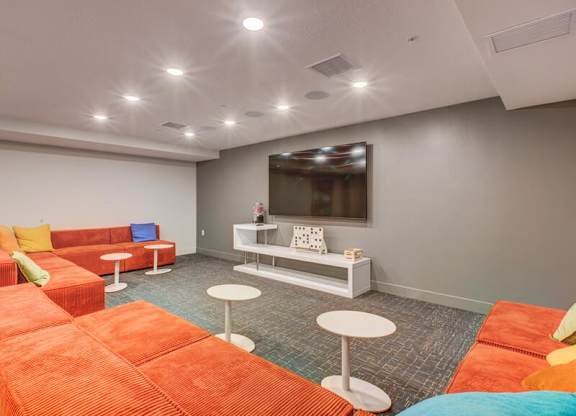 A room with orange and white furniture and a flat screen TV mounted on the wall.