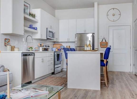 A kitchen with white cabinets and a glass table.