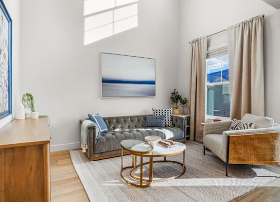 A living room with a grey sofa, a wooden side table, and a large painting on the wall.