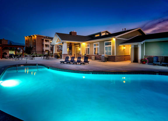 an evening view of the resort style swimming pool in front of the clubhouse at Outlook Apartments for rent in Springville and Provo, UT.