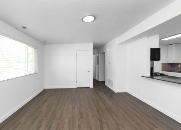 an empty living room with white walls and a window