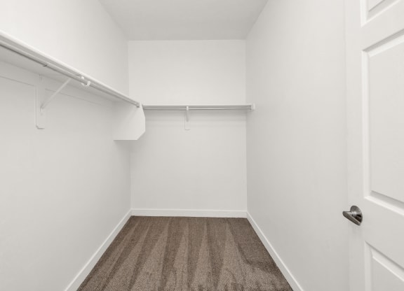 an empty room with white walls and carpet and a white closet