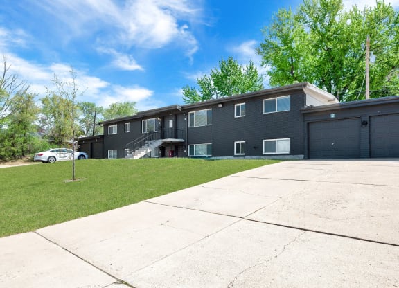the front of an apartment building with a driveway and lawn