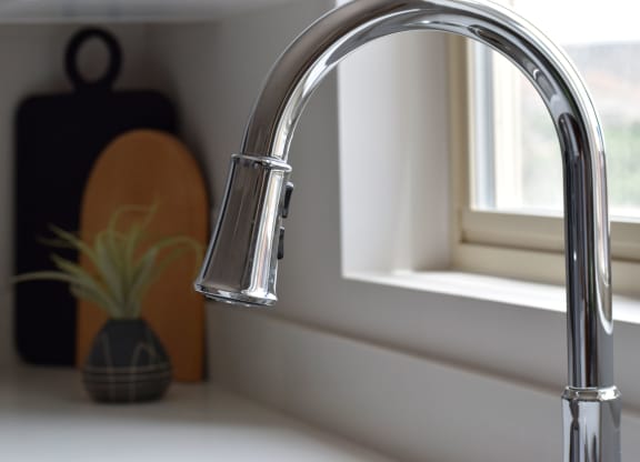 a kitchen sink with a faucet in front of a window