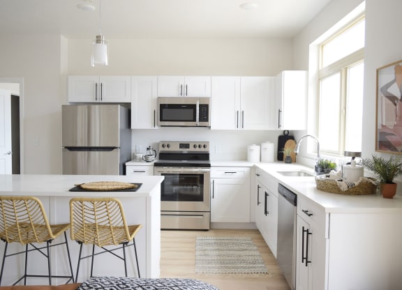 a kitchen with white cabinets and a white island with two stools