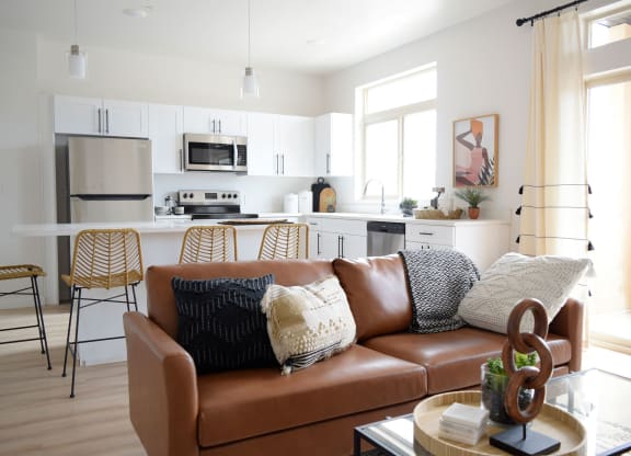 a living room with white walls and a brown leather couch