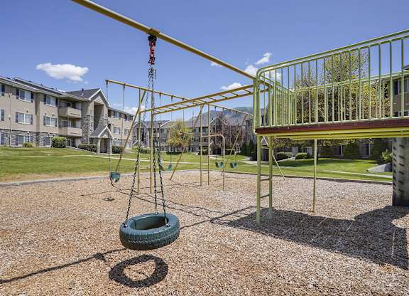 A tire swing hangs from a metal frame in a playground.