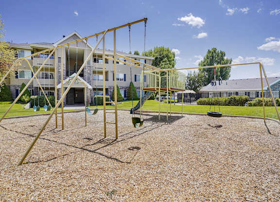 A playground with a swing set and a building in the background.