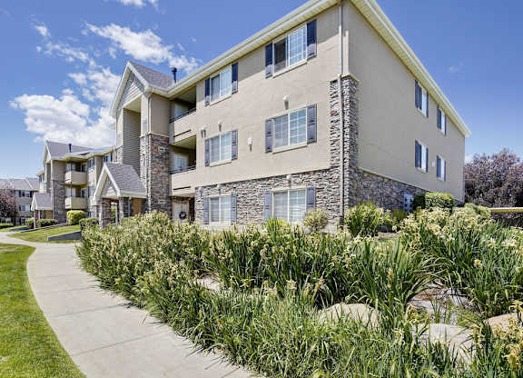 Apartment building with a stone facade and a green lawn in front.