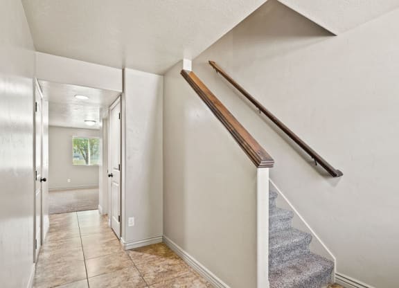 the entryway of a house with stairs and a hallway with a door