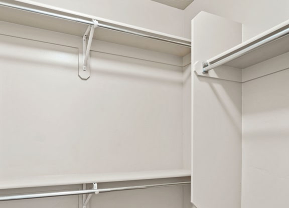a walk in closet with a white wall and a hanging rack on the wall